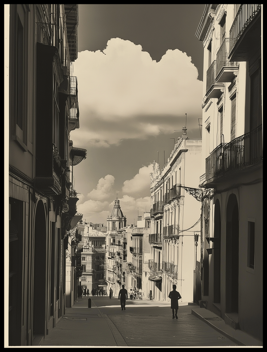 A black-and-white photograph of a street in Valencia, capturing rows of elegant balconies on both sides, a person walking in the foreground, and a beautiful view of historic architecture in the distance under a dramatic sky filled with clouds.